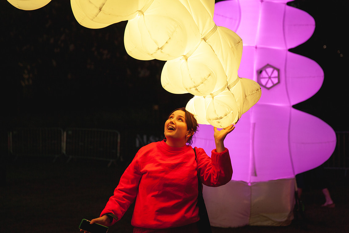 An excited audience member looking up at a giant illuminated, inflated vine